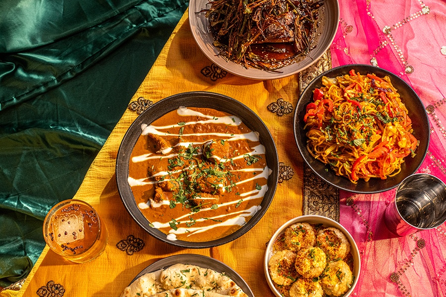 Overhead view of various dishes of Indian food on a colorful background.