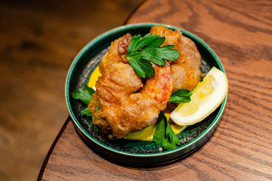 Crispy shrimp tempura sits in a thick yellow sauce.
