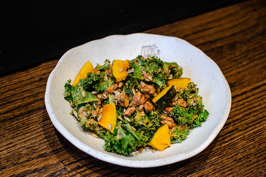 A white plate is full of kale and pumpkin slices.