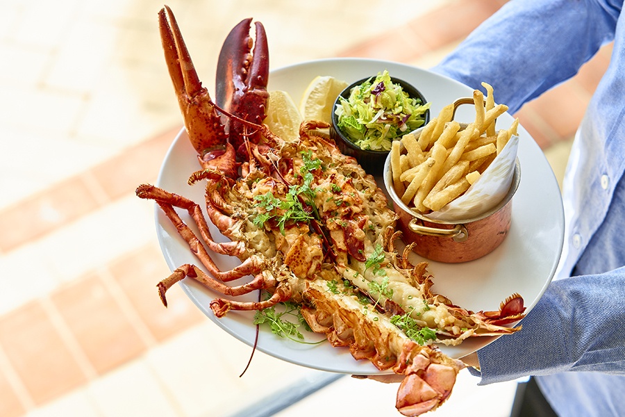 A whole lobster is cut in half and stuffed, accompanied by a side of fries.