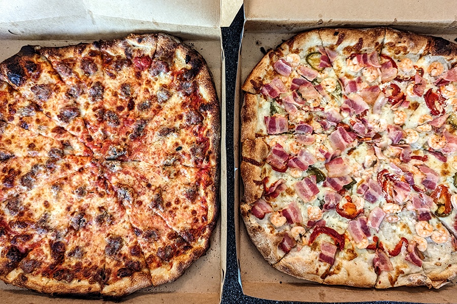 Overhead view of two New Haven-style pizzas in takeout boxes.