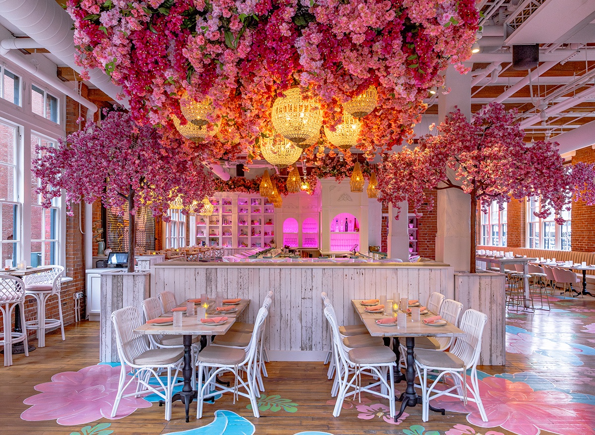 Photo of a pink and white dining room with a ceiling of lush pink flowers.