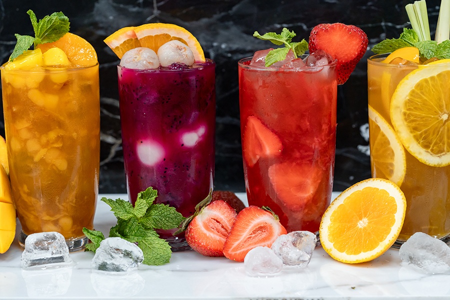 Four colorful glasses of fruity bubble teas are lined up.