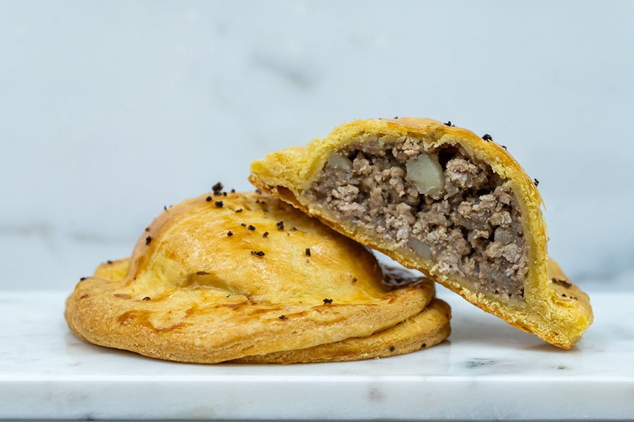 A dome-shaped, French-style meat pie is cut in half to display the filling.