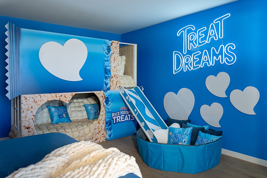 A room is full of Rice Krispies Treats-themed decor, including a bunk bed with a slide and ball pit and a neon sign that says "Treat Dreams."