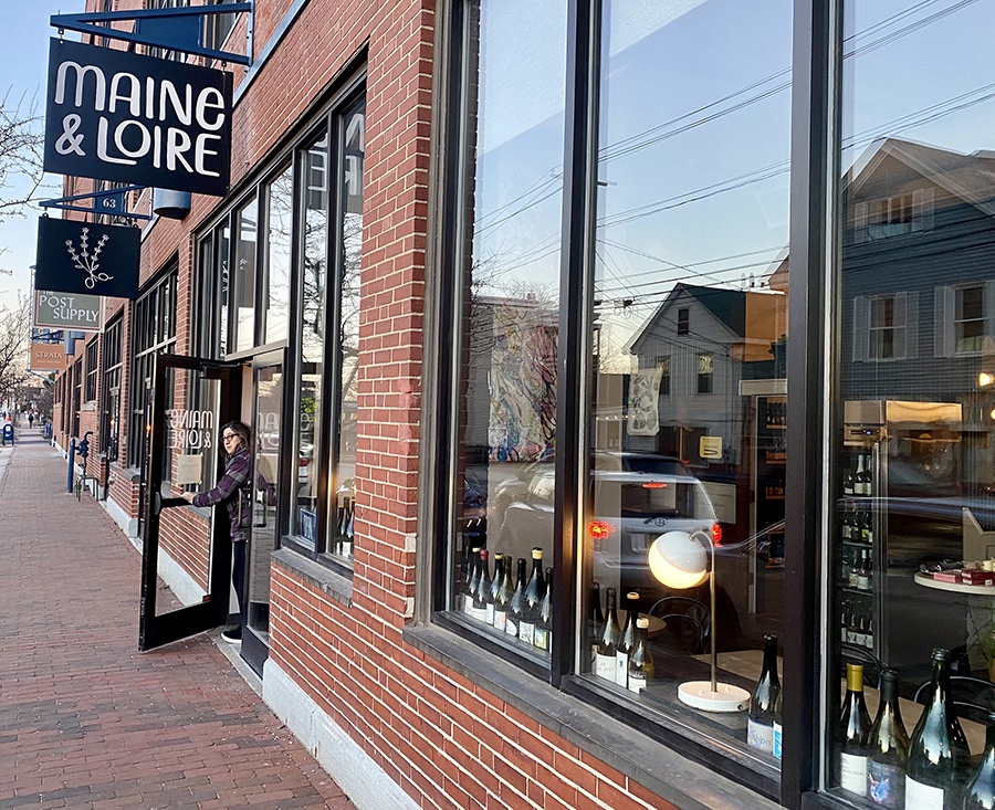 Red brick exterior of a store called Maine & Loire, with lots of wine bottles visible through the large front window.