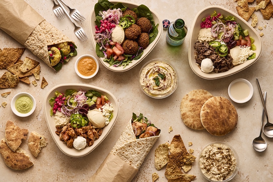 Overhead view of fast-casual Middle Eastern bowls, dips, and pitas.