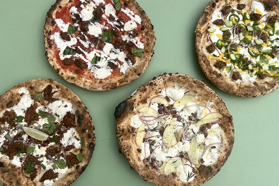 Overhead view of four Neapolitan-style pizzas with various toppings.