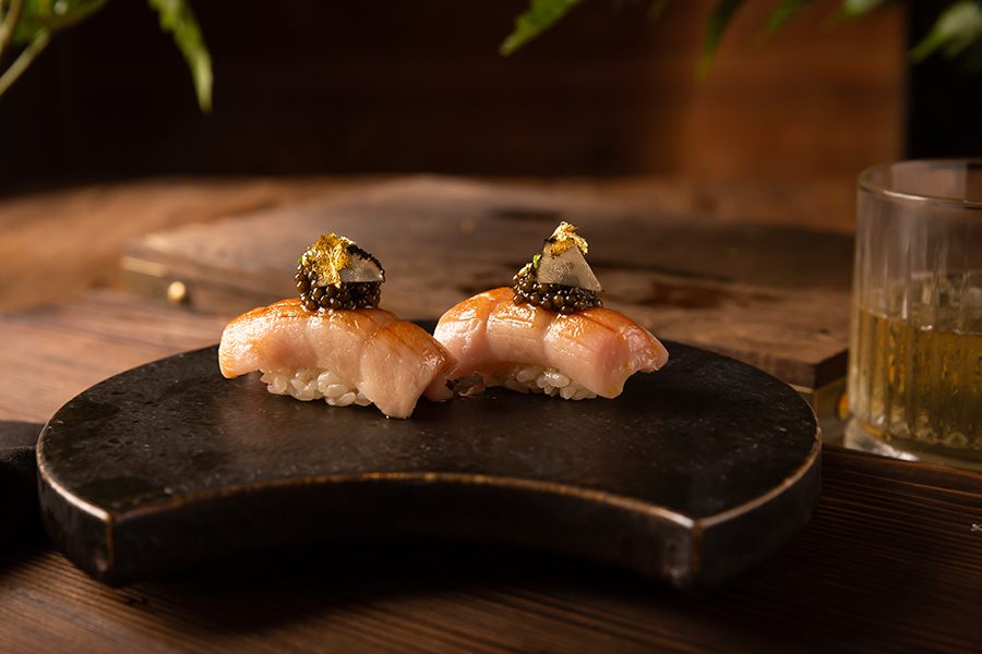 Two pieces of sushi feature fatty tuna topped with caviar and gold flakes.