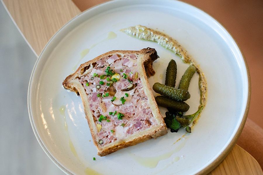 Overhead view of pate en croute with tiny pickles and mustard.