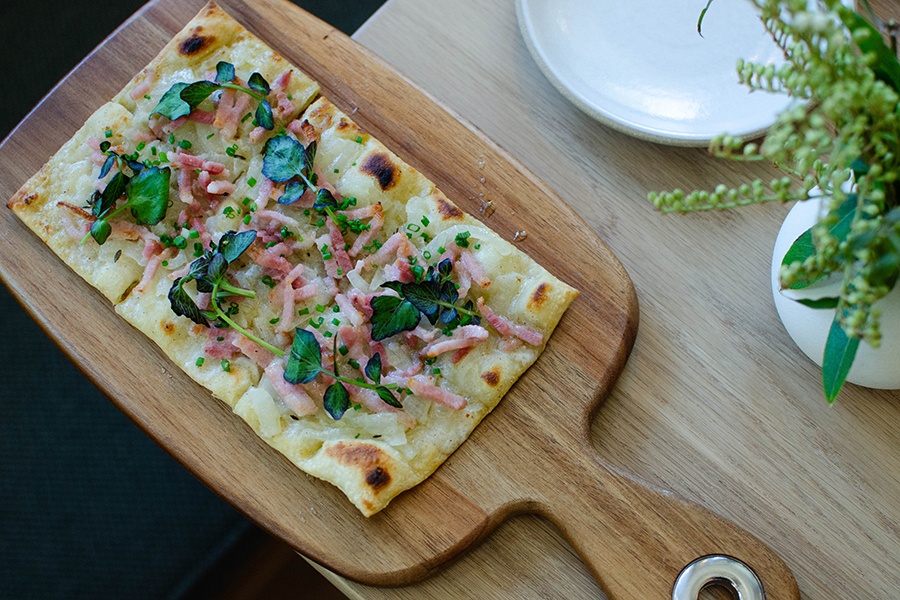 Overhead view of a thin-crust flatbread on a wooden paddle.