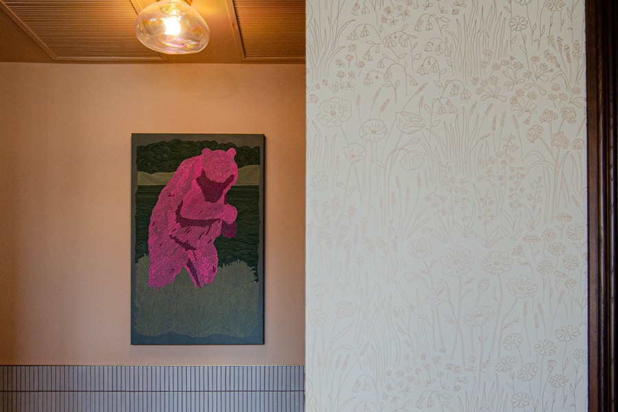 A painting of a pink bear hangs on a restaurant wall.