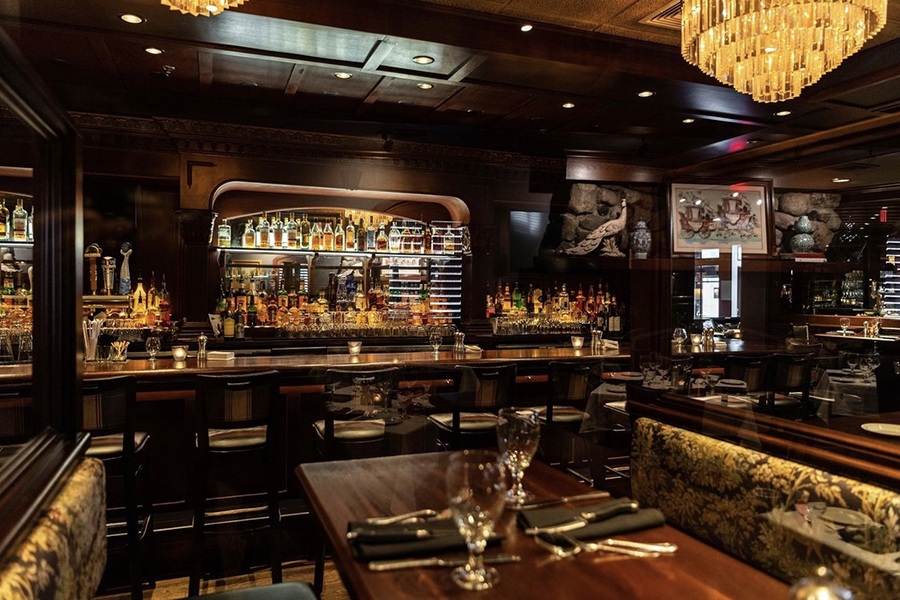 The bar and dining space at an upscale steakhouse, full of dark, glossy wood.