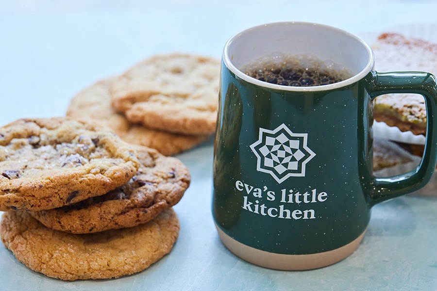 Cookies are stacked next to a green coffee mug that says Eva's Little Kitchen.