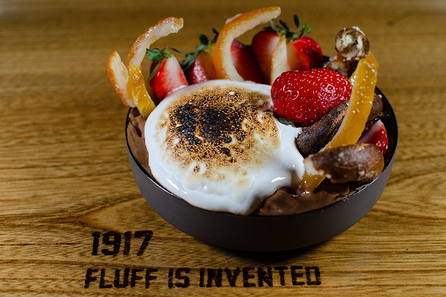 A bowl of chocolate mousse is topped with torched marshmallow fluff, strawberries, and more.