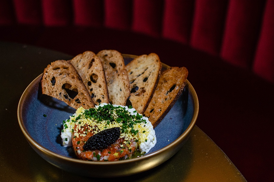 Raw salmon topped with a quenelle of caviar and other toppings, plus bits of toast.