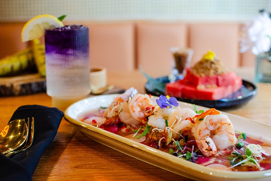 Shrimps sit in a light broth full of herbs and sliced radishes.