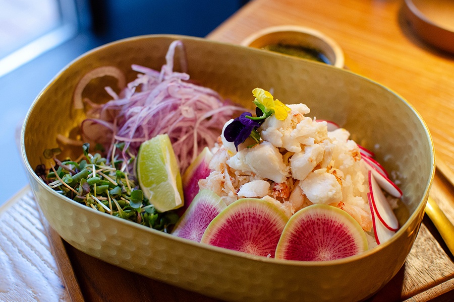 Crab meat sits atop jasmine rice with herbs, red onion, and radishes.