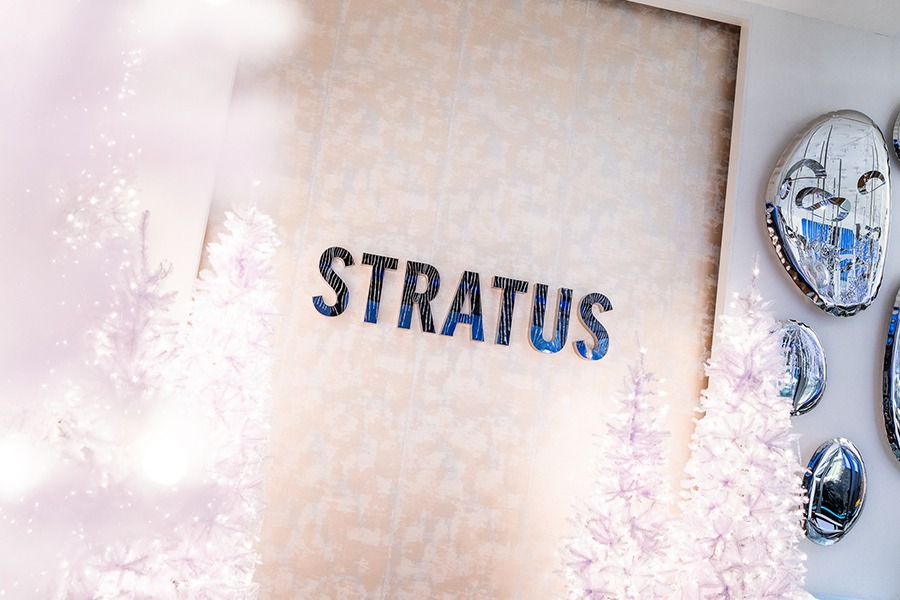 White Christmas trees are displayed in front of a wall that says Stratus in mirrored letters.