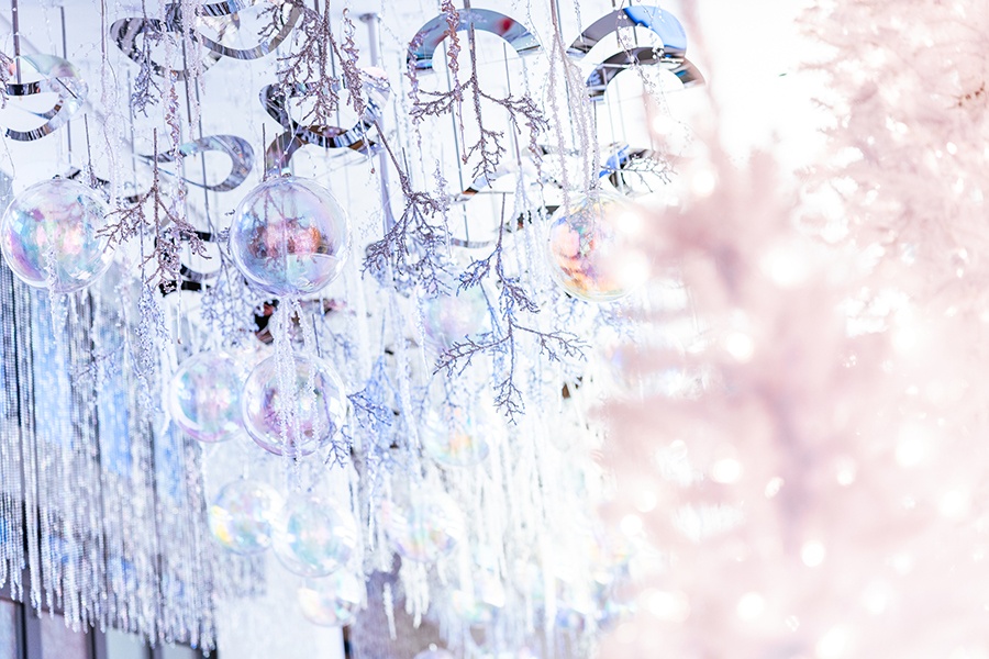 Wintery baubles and silver decorations hang in a bar with white Christmas trees.