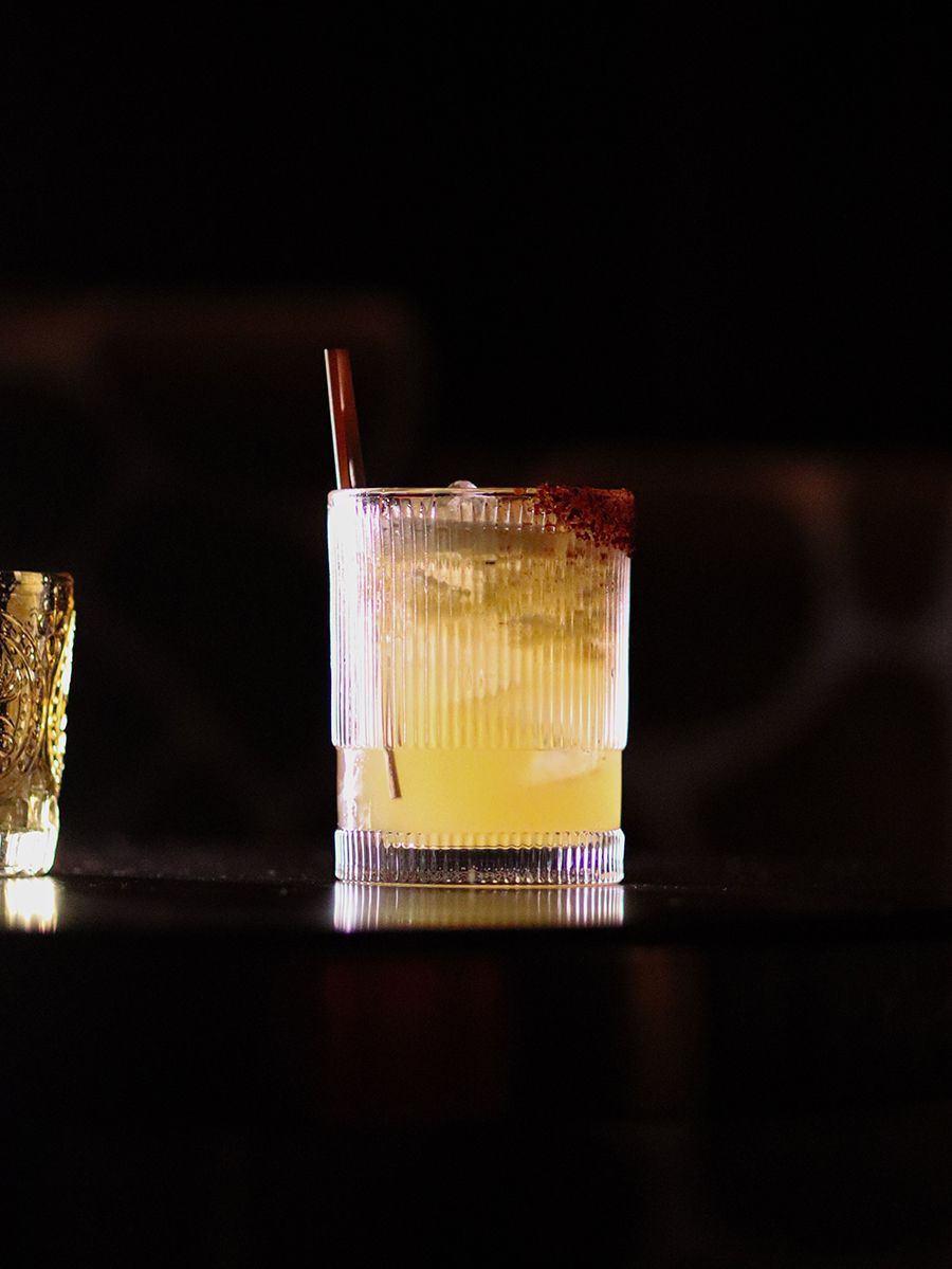 A yellow cocktail on a dark background.