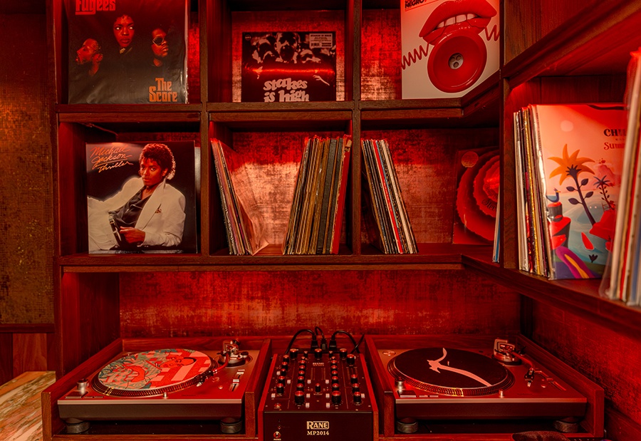 Shelves of records hang over a vinyl sound system inside a bar.