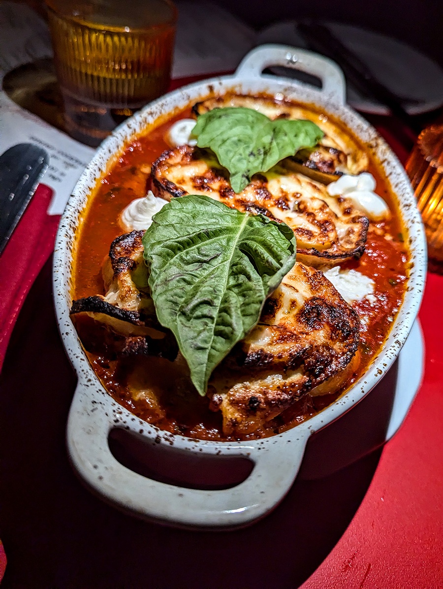 Three big pieces of rolled lasagna sit in an oval bowl of tomato sauce.