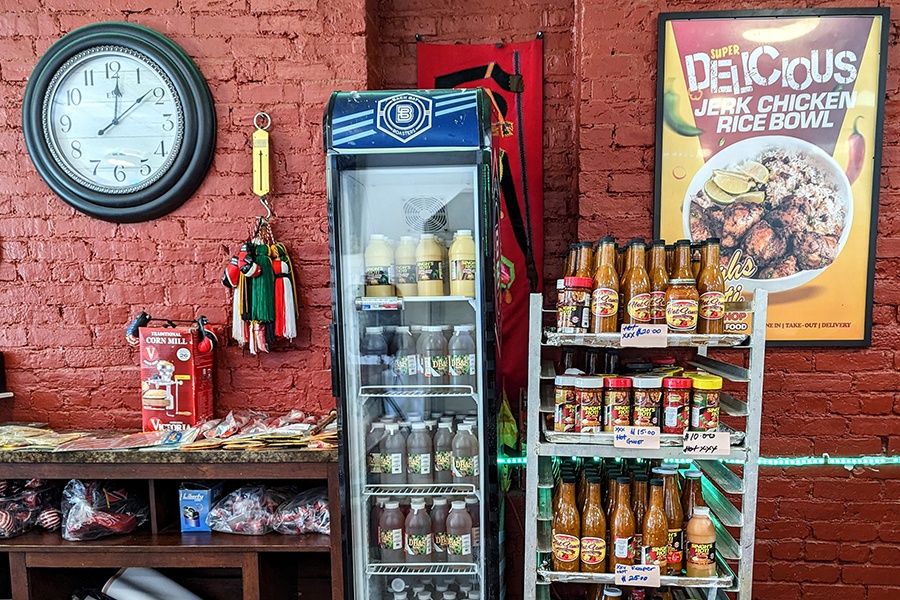 Shelves of hot sauces and a fridge of beverages at a casual restaurant.