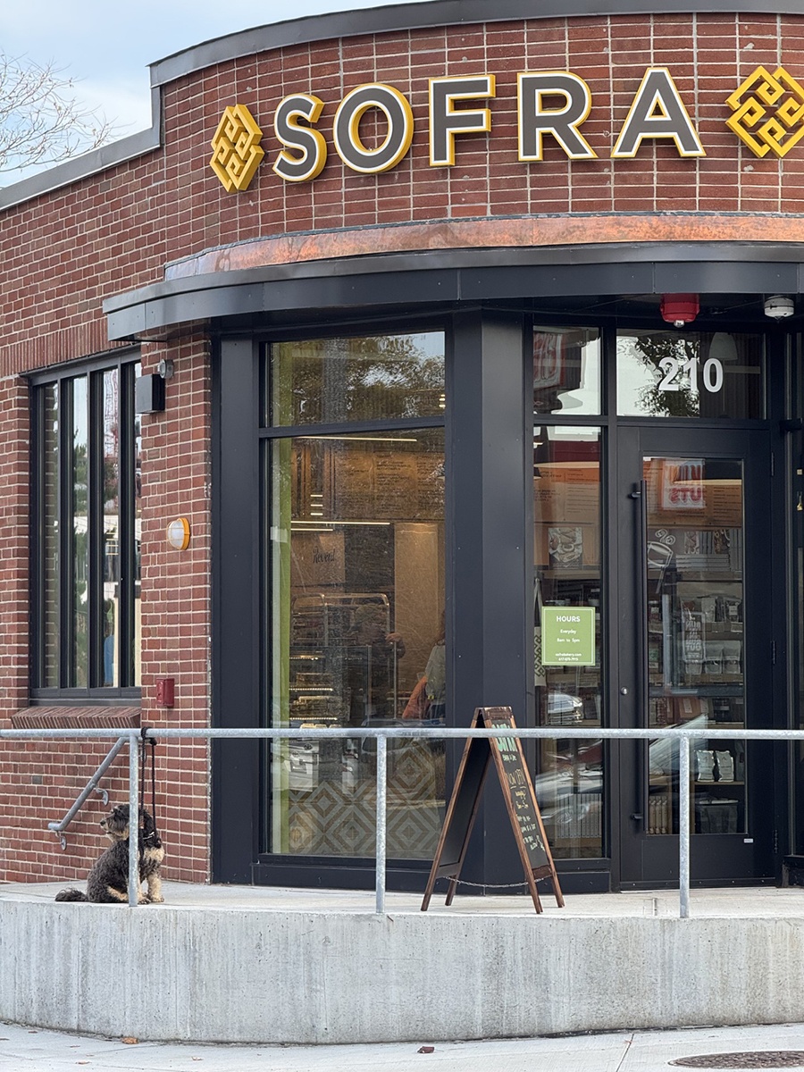 Brick exterior of a one-story building with a curved entrance and signage reading Sofra.