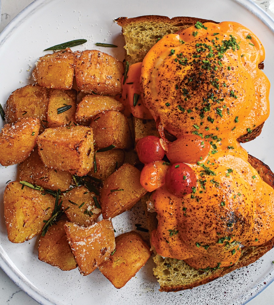 Overhead view of eggs benedict on bread with homefries.