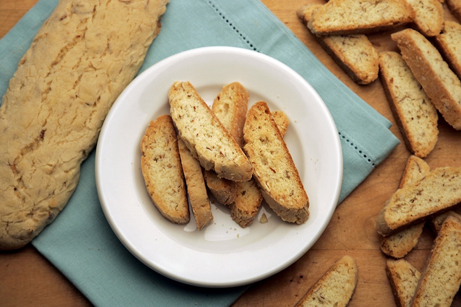 Overhead view of a plate of biscotti next to an uncut loaf of biscotti.