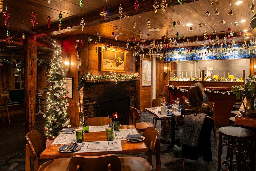 A cozy restaurant is decorated for Christmas with ornaments, a tree, and other festive decor.