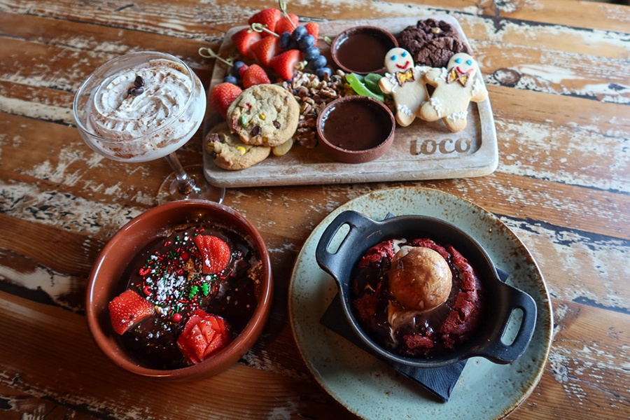 A spread of holiday season desserts and a cocktail on a wooden table.