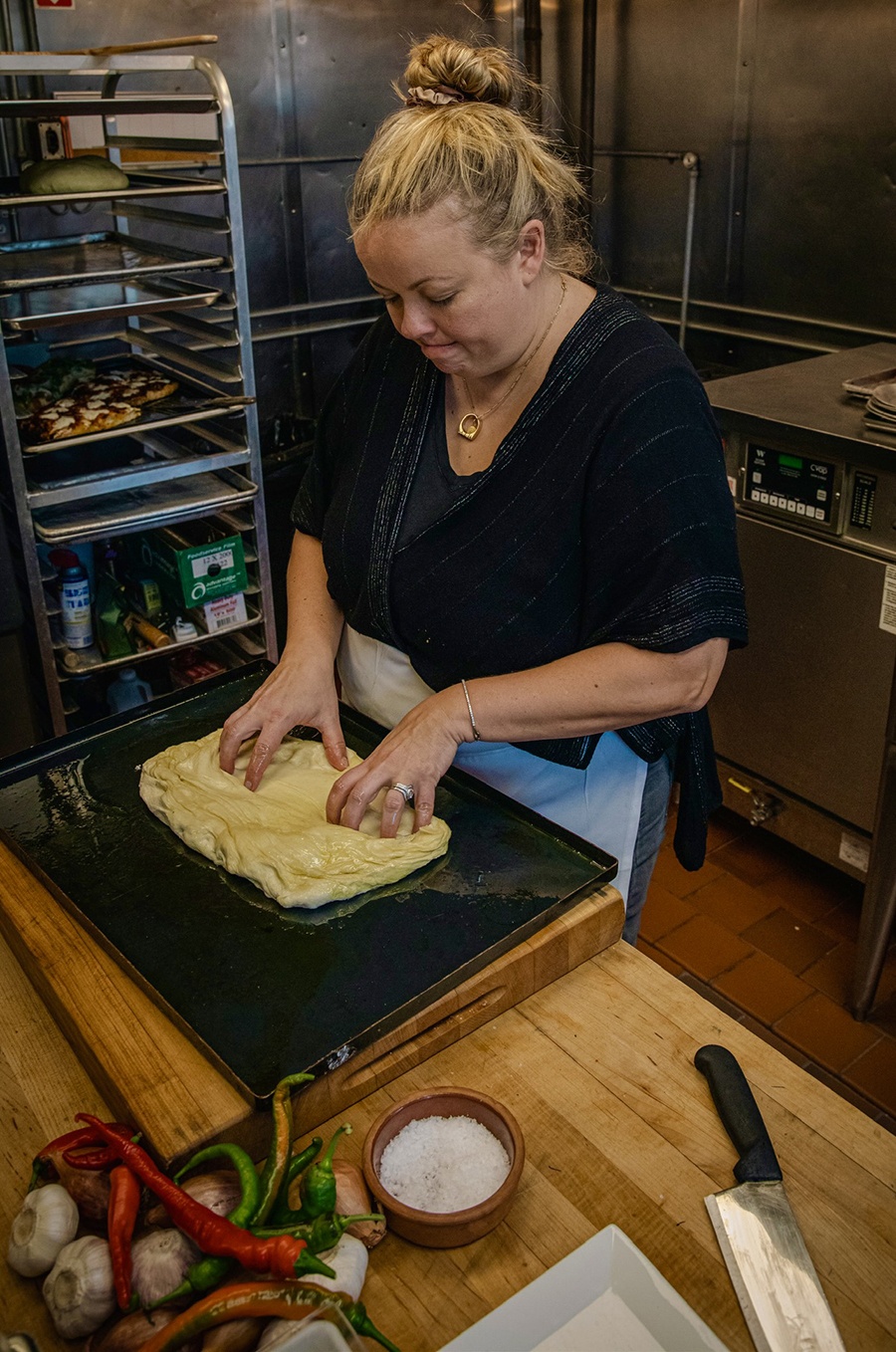 A chef works with dough inside a restaurant kitchen.