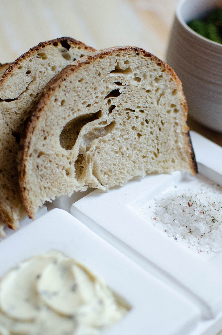 Slices of fresh bread are presented next to butter and an herb-infused salt.