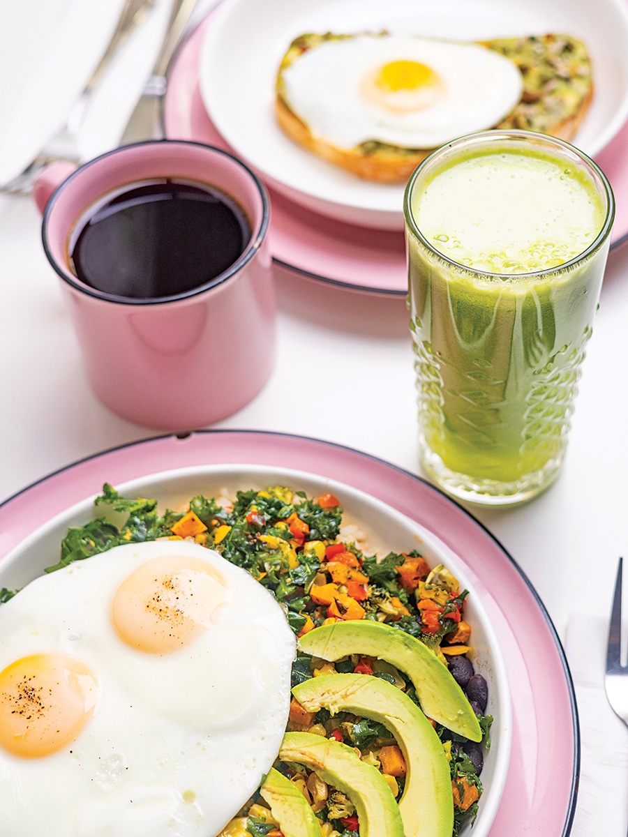 Eggs, avocado, a green smoothie, and more, served on pale pink plates.