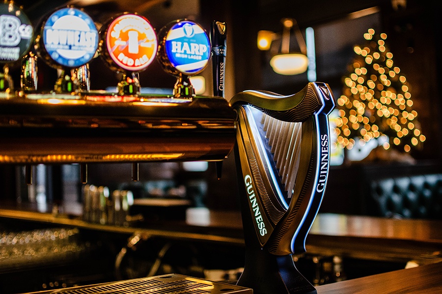 A harp-shaped Guinness tap is visible on a wooden bar inside a restaurant.