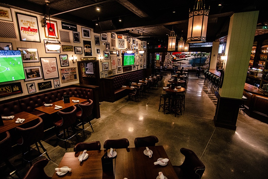 A dimly lit interior of a large restaurant and bar with televisions and lots of Irish-themed artwork.