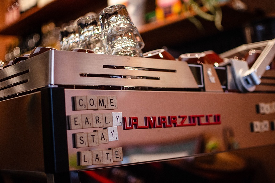 Scrabble tile magnets on an espresso machine read "come early stay late"