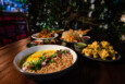 Several Indian dishes, including pakora and dal with rice, are spread across a wooden table.