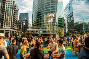 People gather at a beer garden among city skyscrapers.