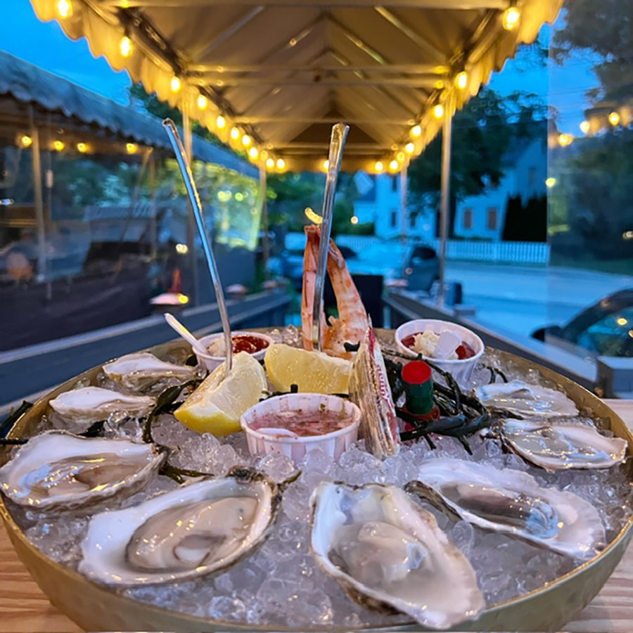 A tray of raw oysters on ice with the usual accoutrements.
