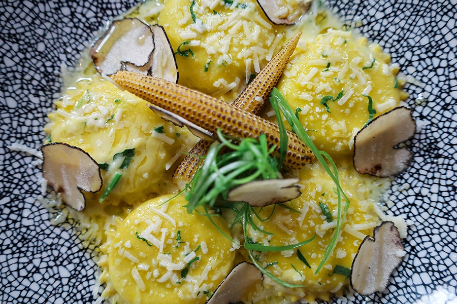 Overhead view of a ravioli, truffle, and baby corn dish.
