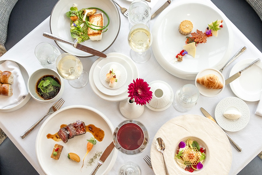 Overhead view of a table of fancily plated dishes, including steak, seafood, and dessert.