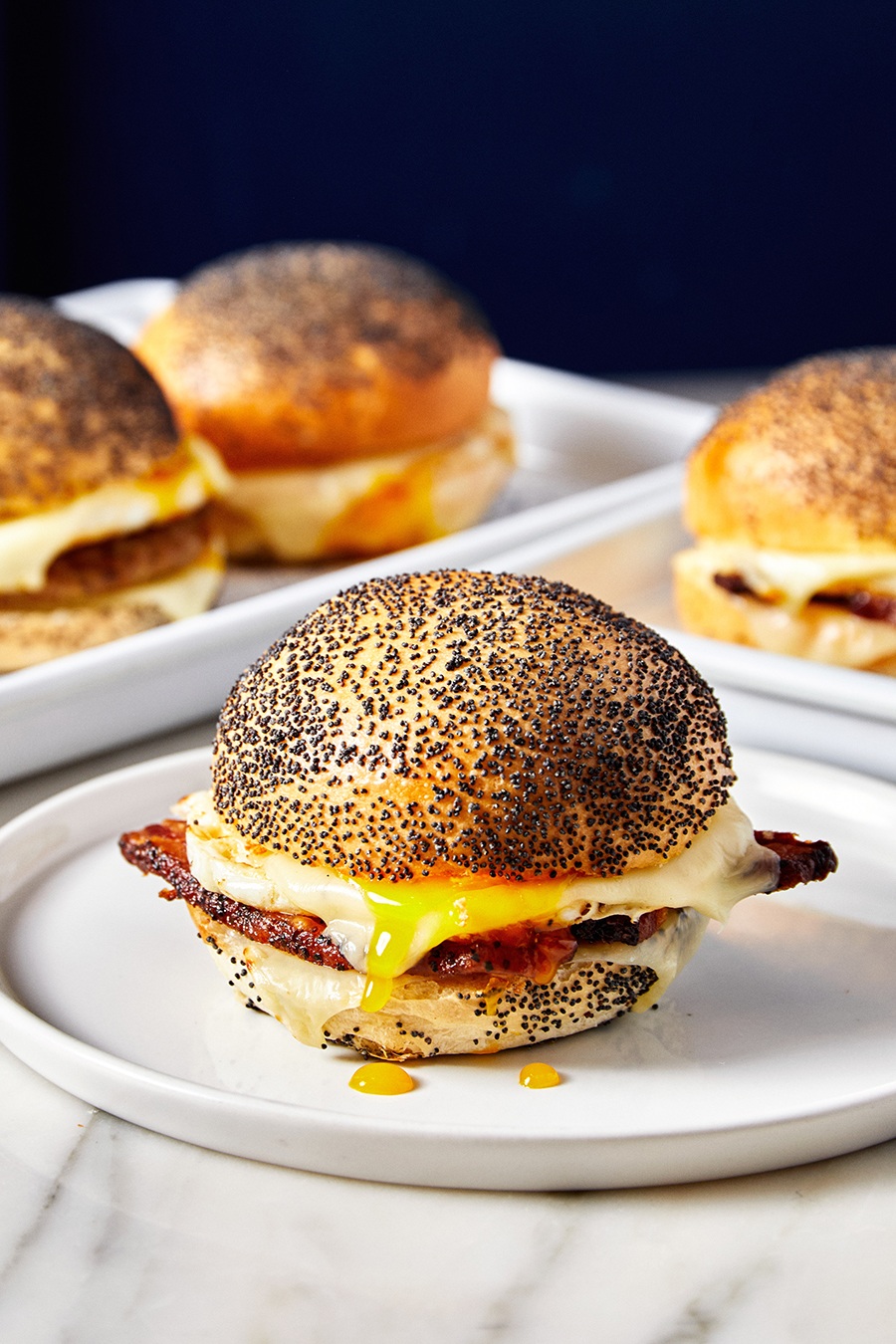 Runny eggs, bacon, and cheese on a poppyseed bun.