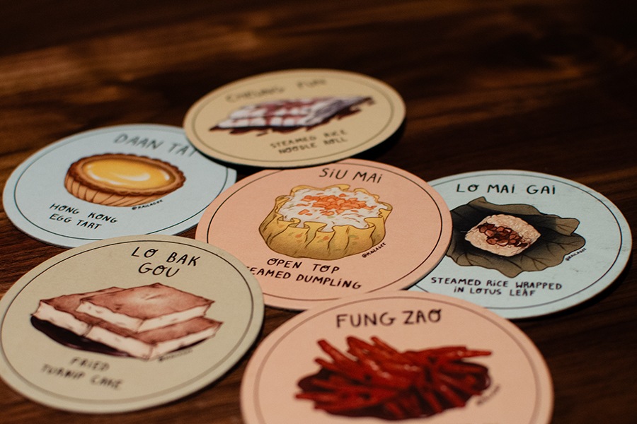 Half dozen colorful drink coasters each feature a different hand-drawn dim sum dish.