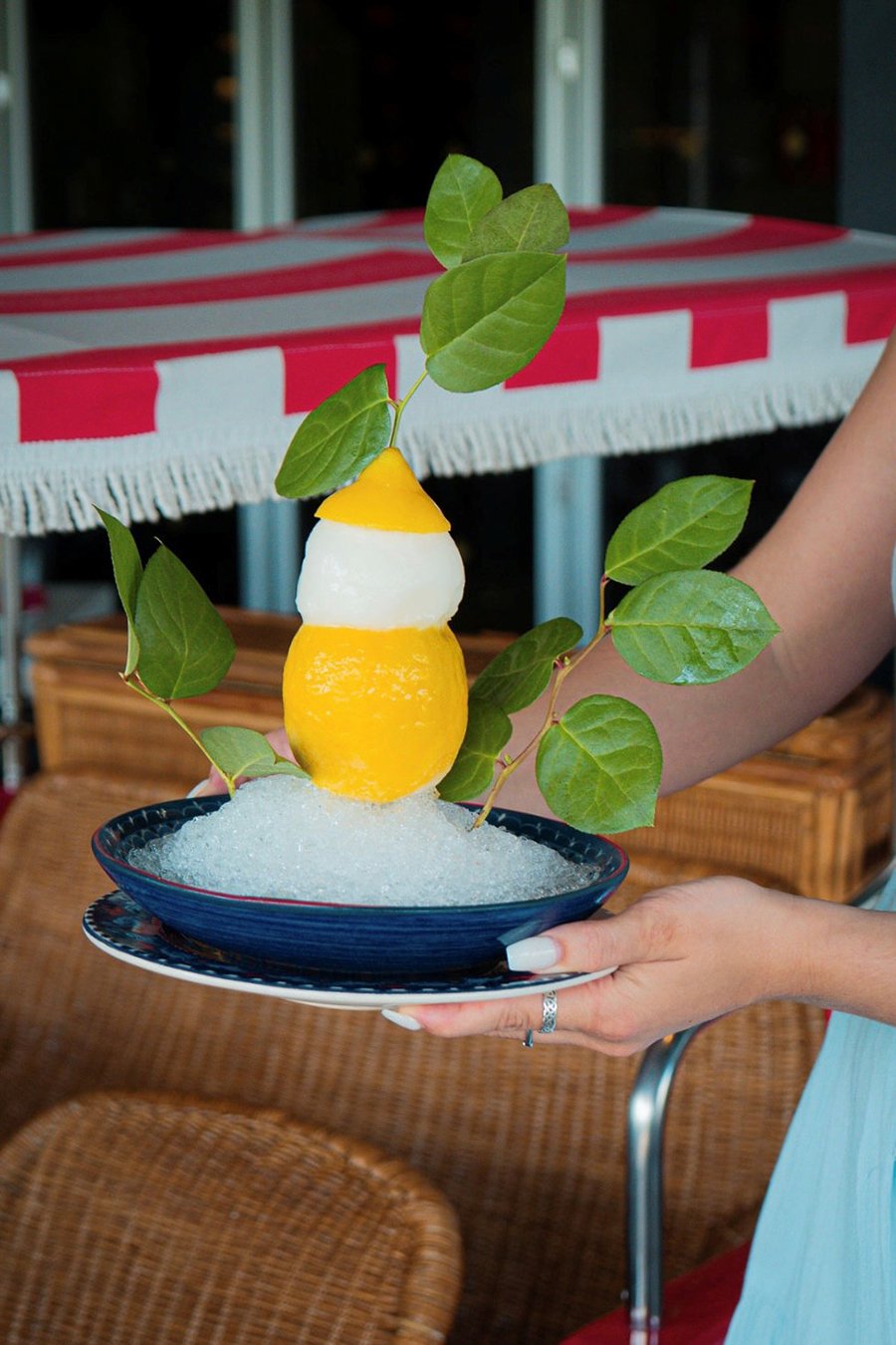 A lemon is filled with lemon sorbet and presented to a table at a restaurant.