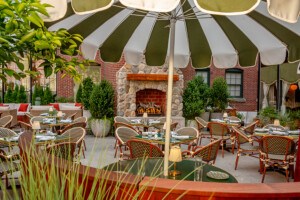 An Italian-inspired large restaurant patio with green-and-white-striped umbrellas and a fireplace.